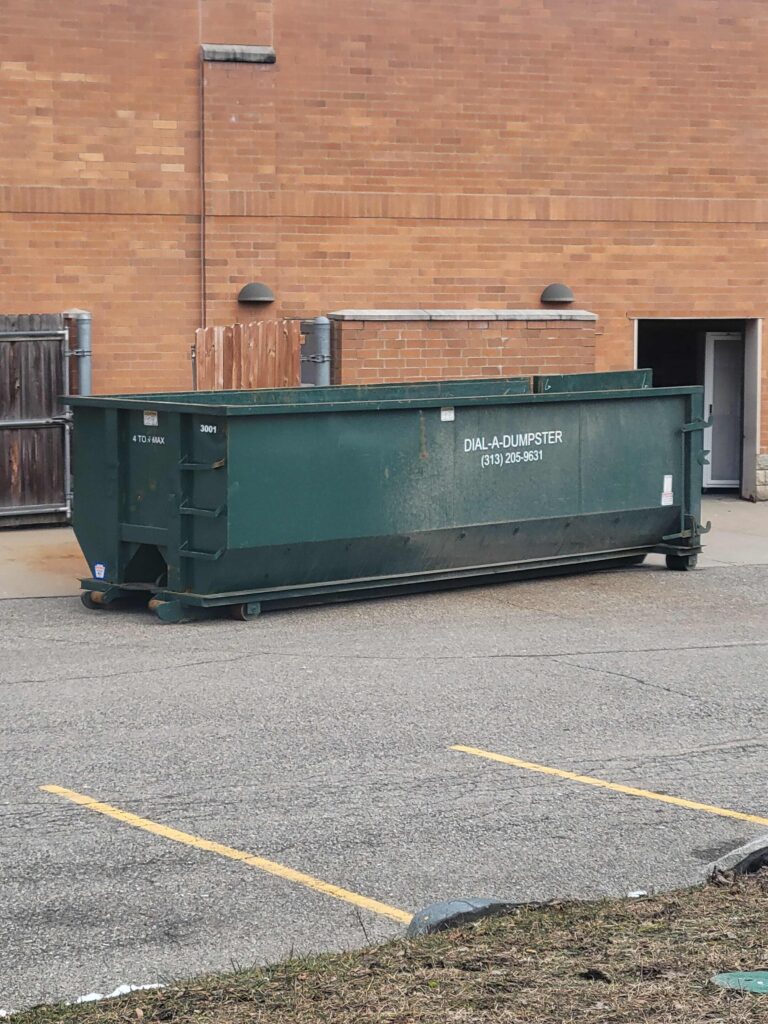 A green dumpster parked in a parking lot. dumpster rental service