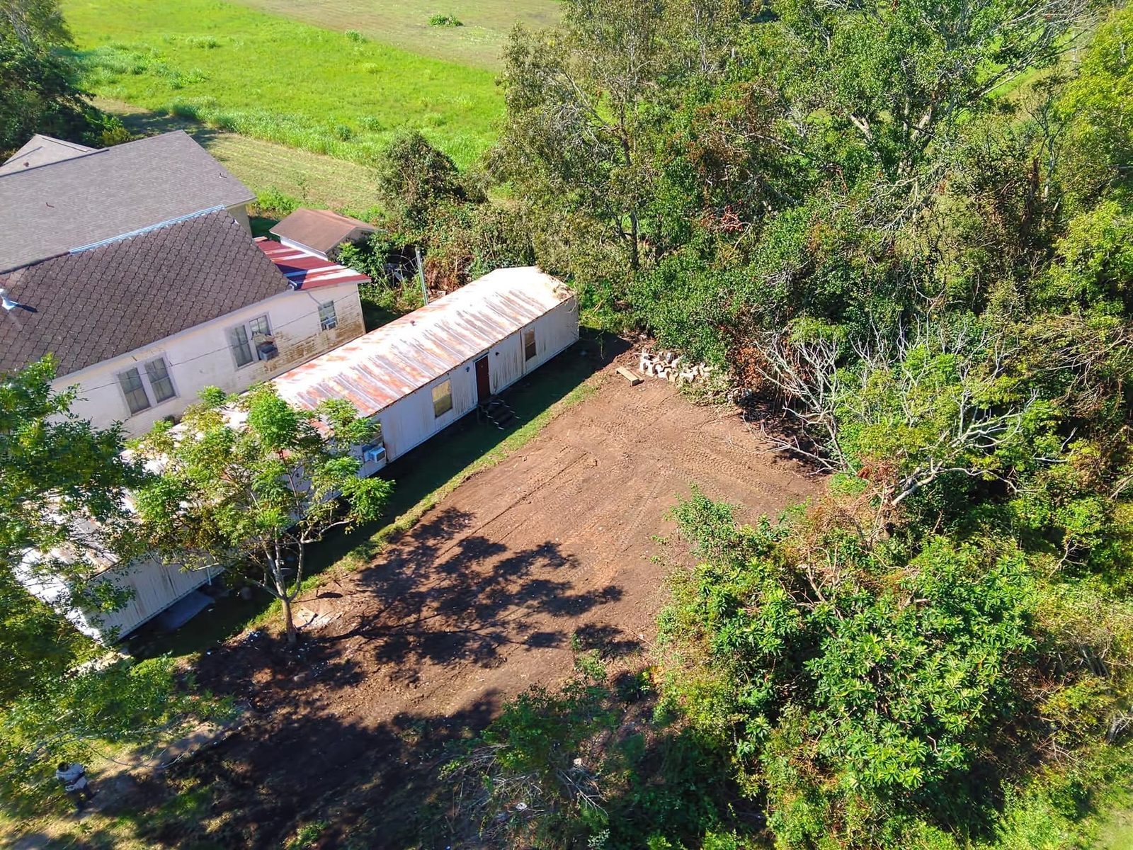 After demolition: the same lot seen from above, cleared down to bare dirt beside the neighboring buildings